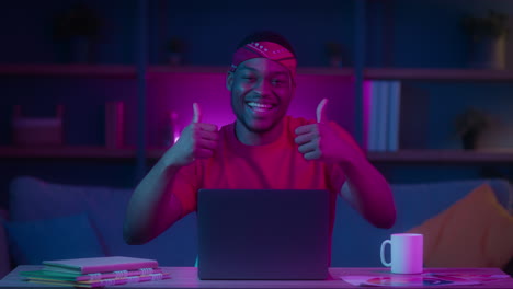 happy man giving thumbs up while working on laptop