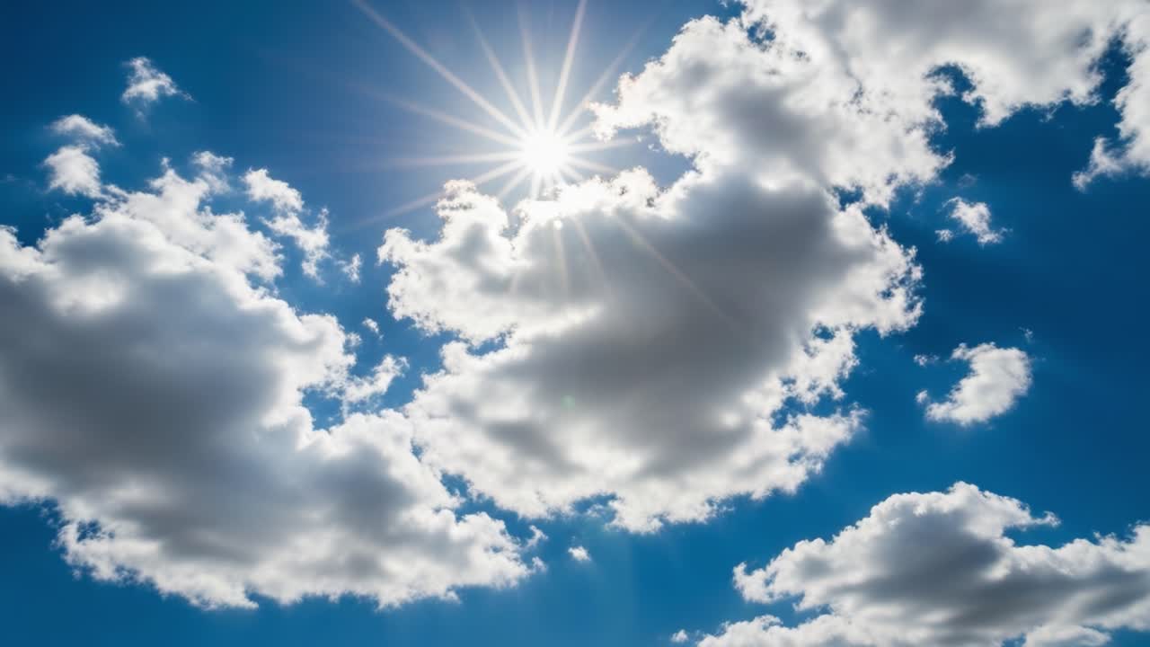 Солнце светит сквозь облака на голубом небе.