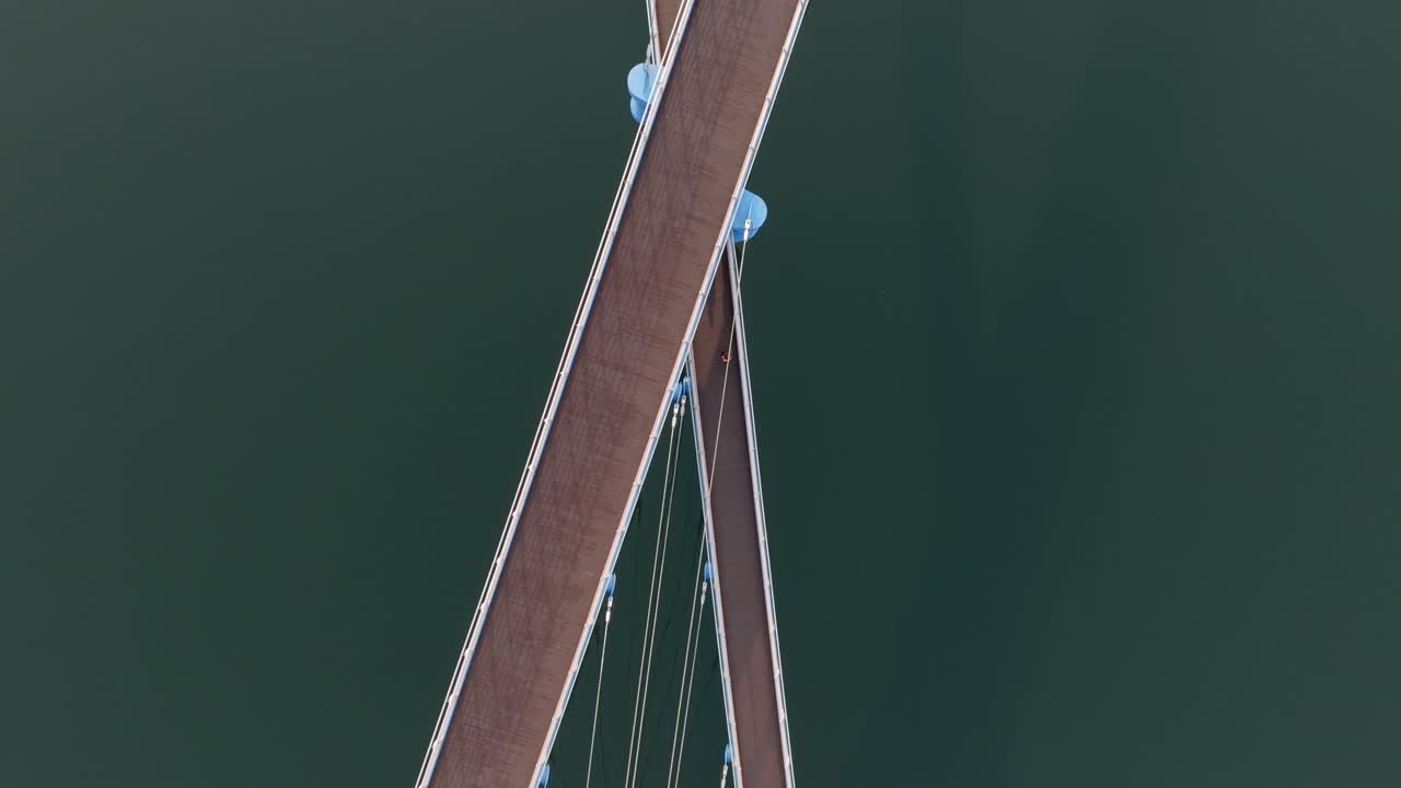Tracking drone view of X-shaped bridge and clean water reflection at Masan Marine Park, South Korea.