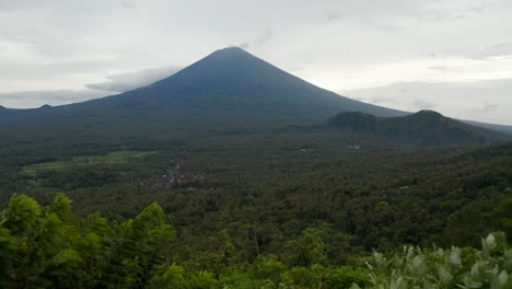 Man-running-towards-the-lookout-point-for-Mount-Agung-above-rainforest-in-Bali.-Tourist-looking-at-large-mountain-peak-rising-above-the-jungle-in-Indonesia