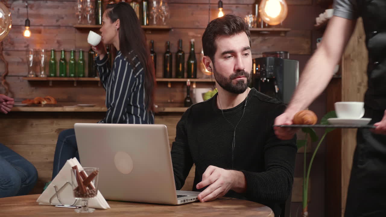 Homem trabalhando em um laptop em um café