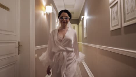 bride in boudoir dress walking to window, wedding morning preparations, woman in night gown and veil