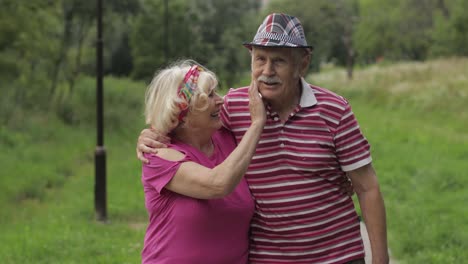 una pareja caucásica anciana caminando en el parque abrazándose. un hombre anciano camina con una mujer. marido, esposa