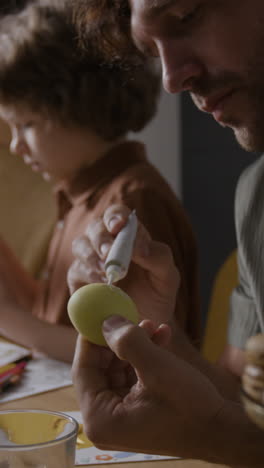 father and child decorating easter eggs