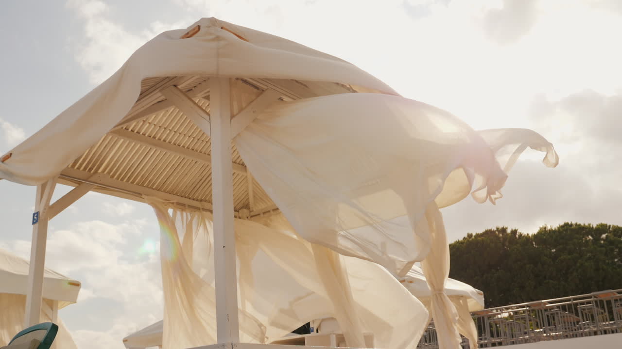 해변 휴양지에서 바람에 캐노피가 있는 해변 선베드