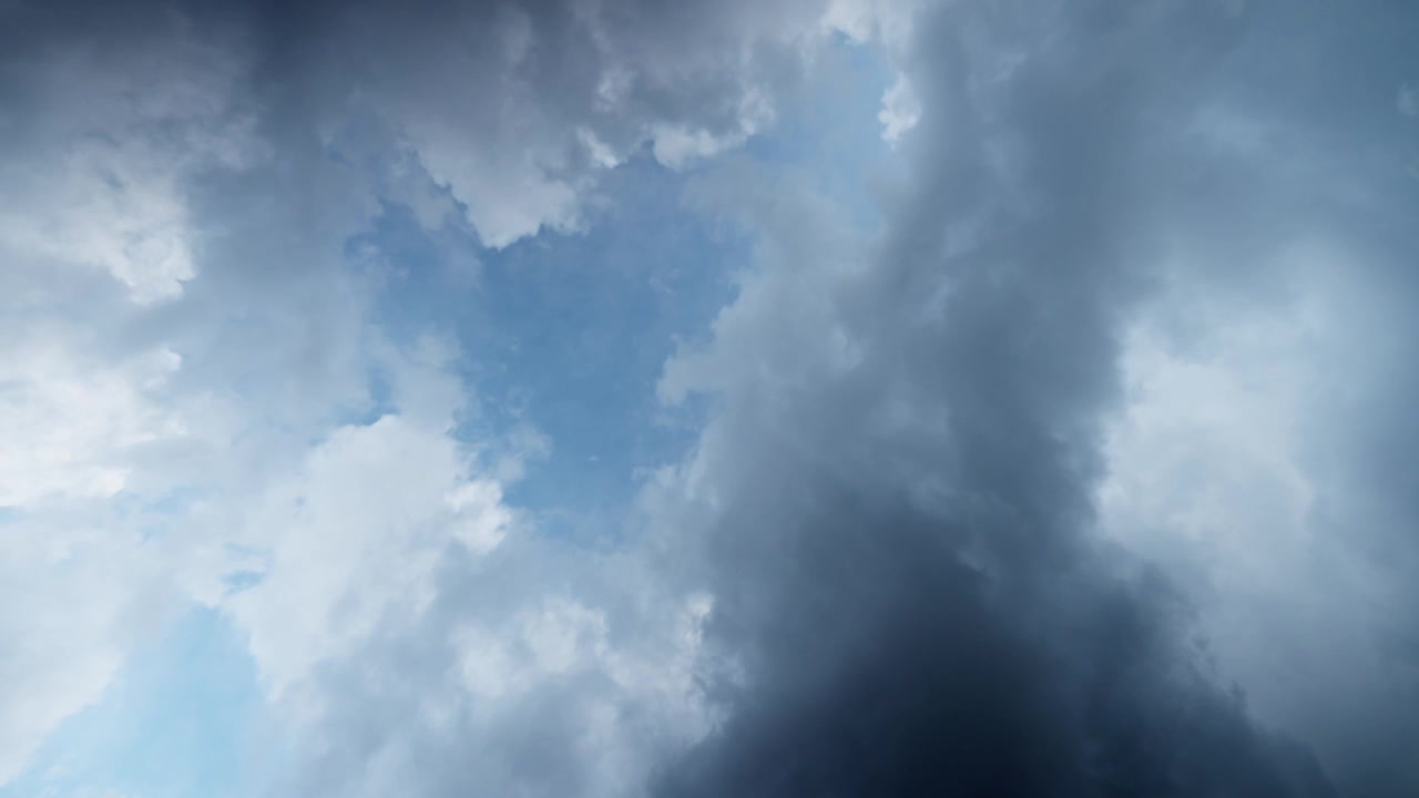 Dark storm clouds drifting across sky before rainfall with dramatic natural atmosphere, darkening blue sky with grey and white ominouse covering