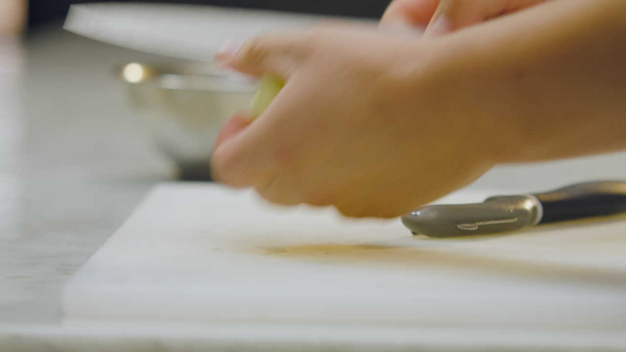 Close-up of a chef cutting a peeled apple with a knife on a chopping board