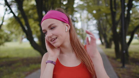 Portrait-of-athletic-sport-runner-girl-training,-listening-favorite-music-song-in-earphones-in-park