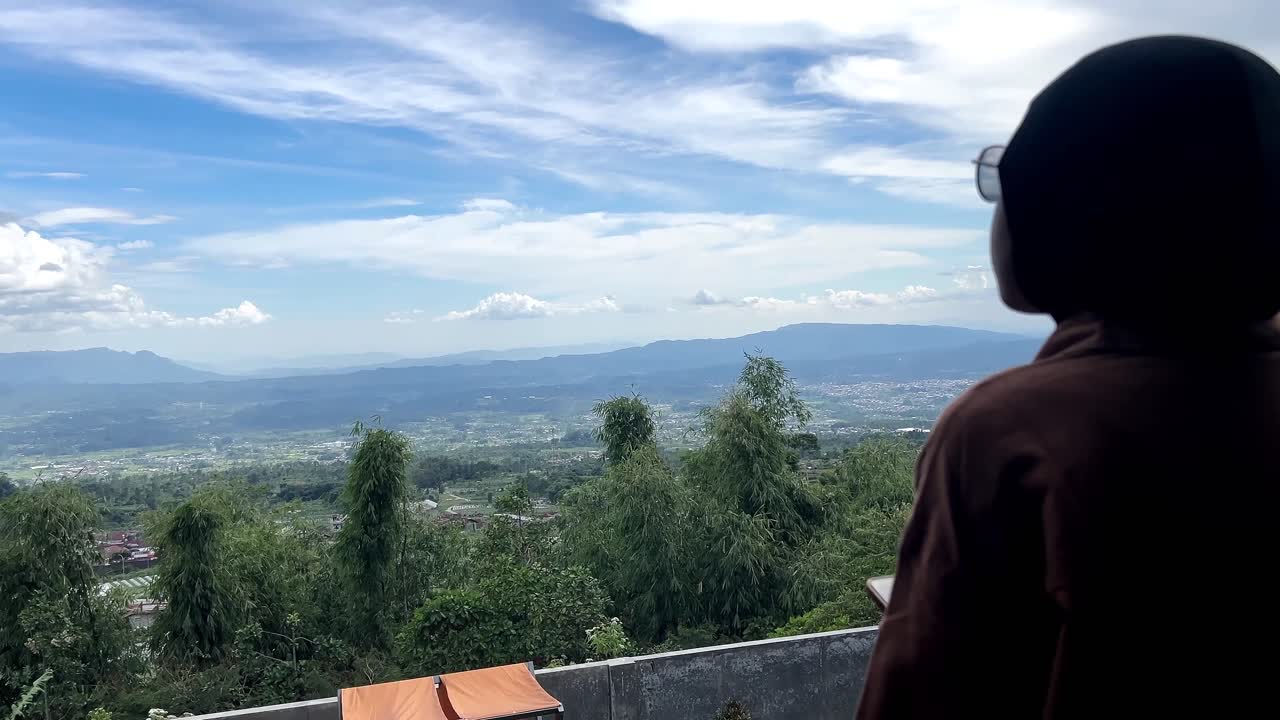 Fokuswechsel-Aufnahme: Muslimische Touristin hält Handy mit Blick auf malerisches Hochland