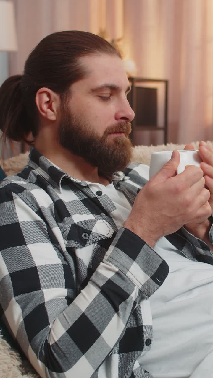 Young man lying with coffee mug at home sofa calm quiet break easy smile stressfree peace vibe