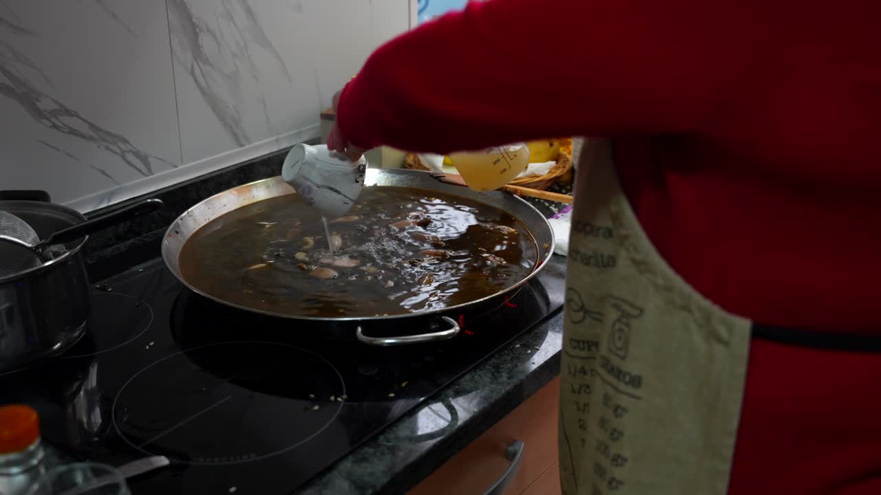 Woman pouring water in a small cup to add it to rice