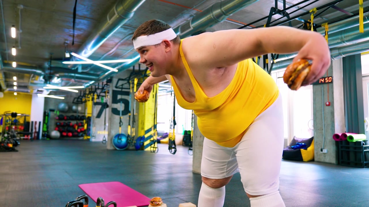 Uomo in sovrappeso che si allena con hamburger come pesi in palestra