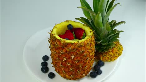 stop motion de una piña que se abre y de la que salen fresas y arándanos