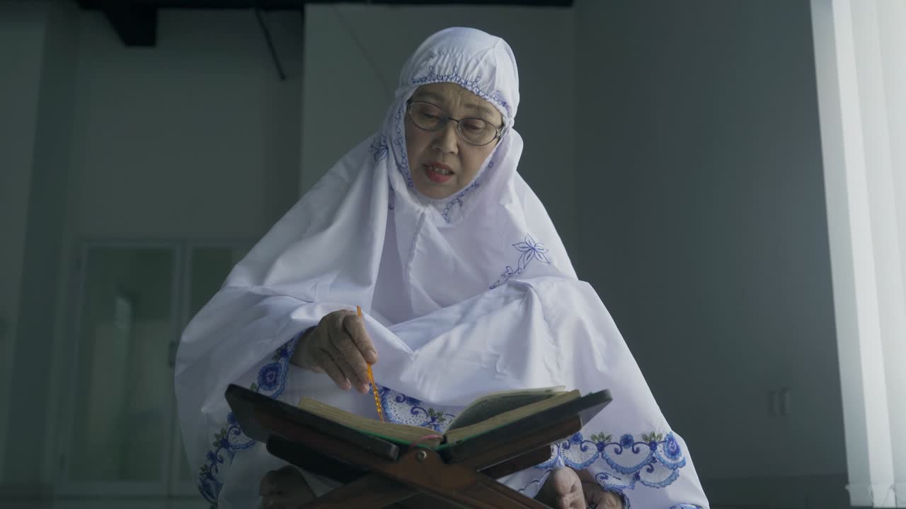 mujer mayor leyendo el corán después de hacer salat