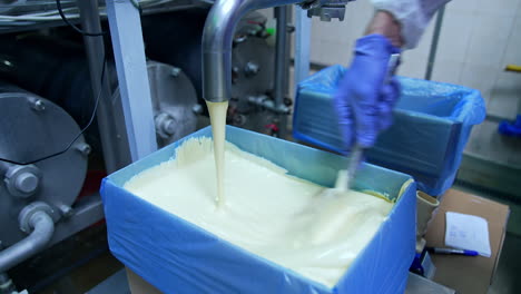 processing of butter at dairy plant. butter pouring from the pipe into the container