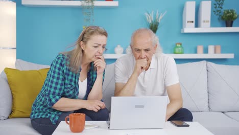 the couple is upset by what they see on the laptop.