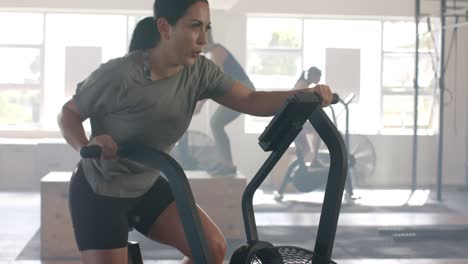 mujer caucásica determinada entrenando en bicicleta elíptica en el gimnasio, en cámara lenta