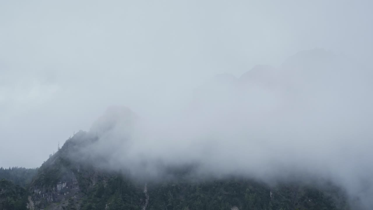 Timelapse of moving fog covering mountain, static