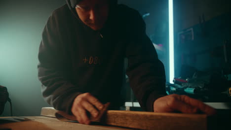 carpintero aficionado lustrando la superficie de una tabla de madera para prepararla para la pintura