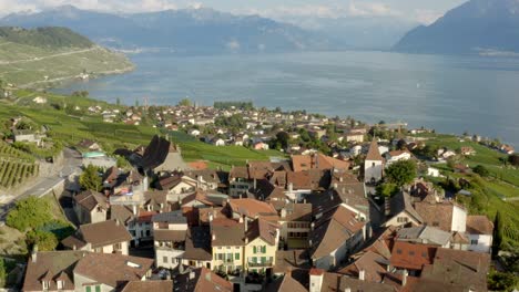 órbita aérea lenta alrededor del típico pueblo suizo en el lago léman de viñedos de lavaux y montañas en el fondo