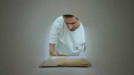 young man taking parcels and envelopes from mailbox