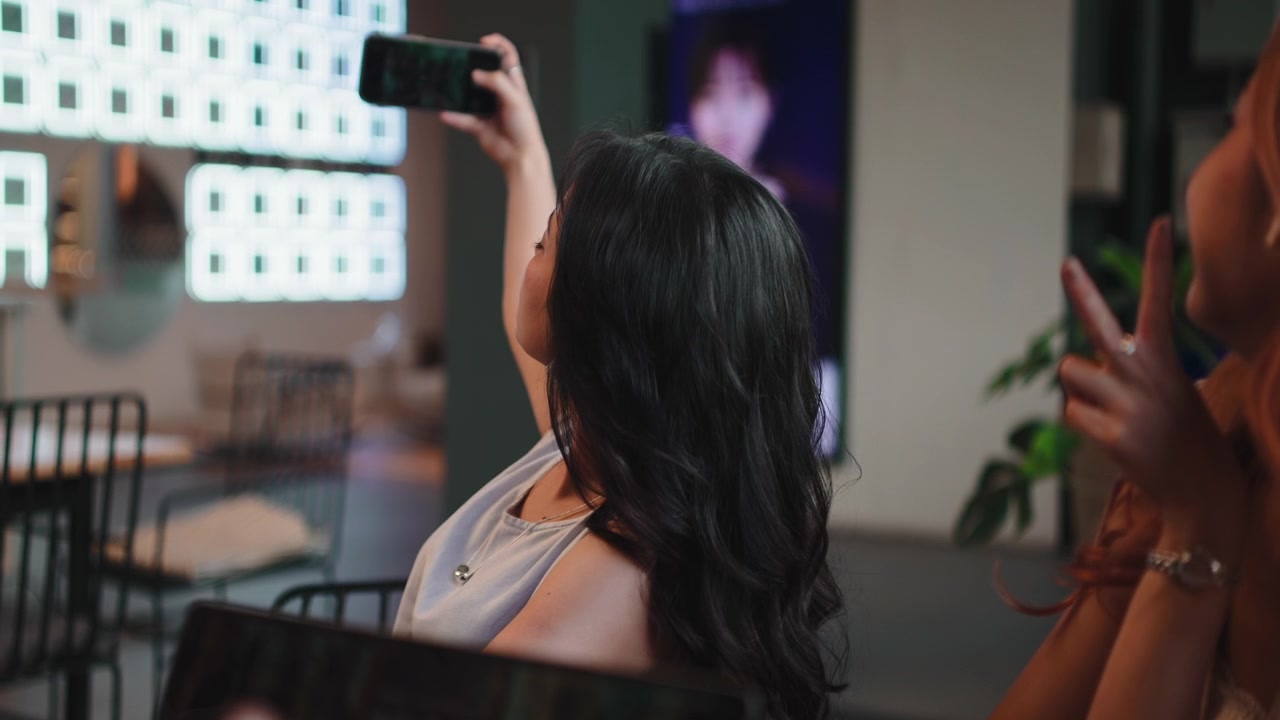 Dos mujeres jóvenes tomándose una selfie juntas en un café moderno
