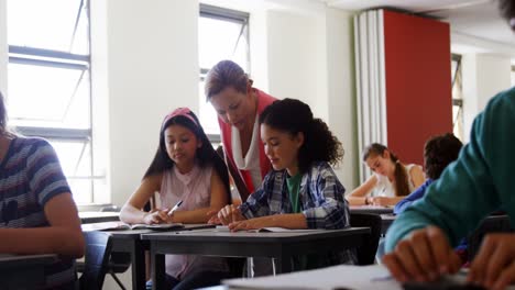 teacher helping students with their homework in classroom