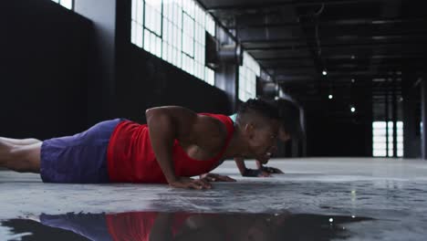 hombre y mujer afroamericanos haciendo flexiones en un edificio urbano vacío