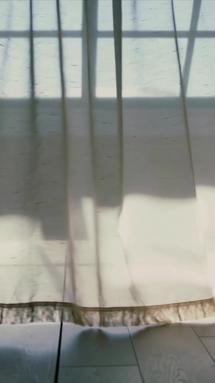 Vertical video: Billowing by gust, drape shifting on floor at home, grid shadow and ruffled hem
