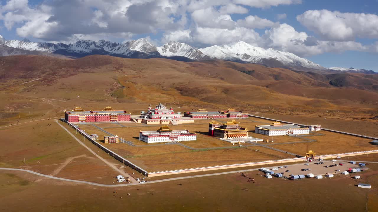 el retroceso aéreo revela una extensión de montañas blancas y templos en las praderas de tagong de sichuan, china.