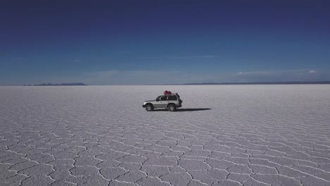 tracking shot of a vehicle driving through the bolivian salt flats