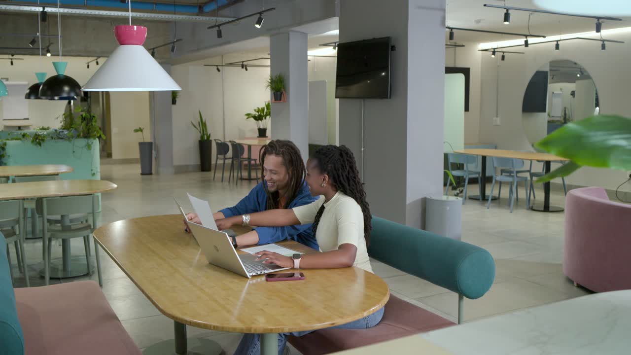 African American pair at office man reaching pointing at laptop, woman typing paper finishing work