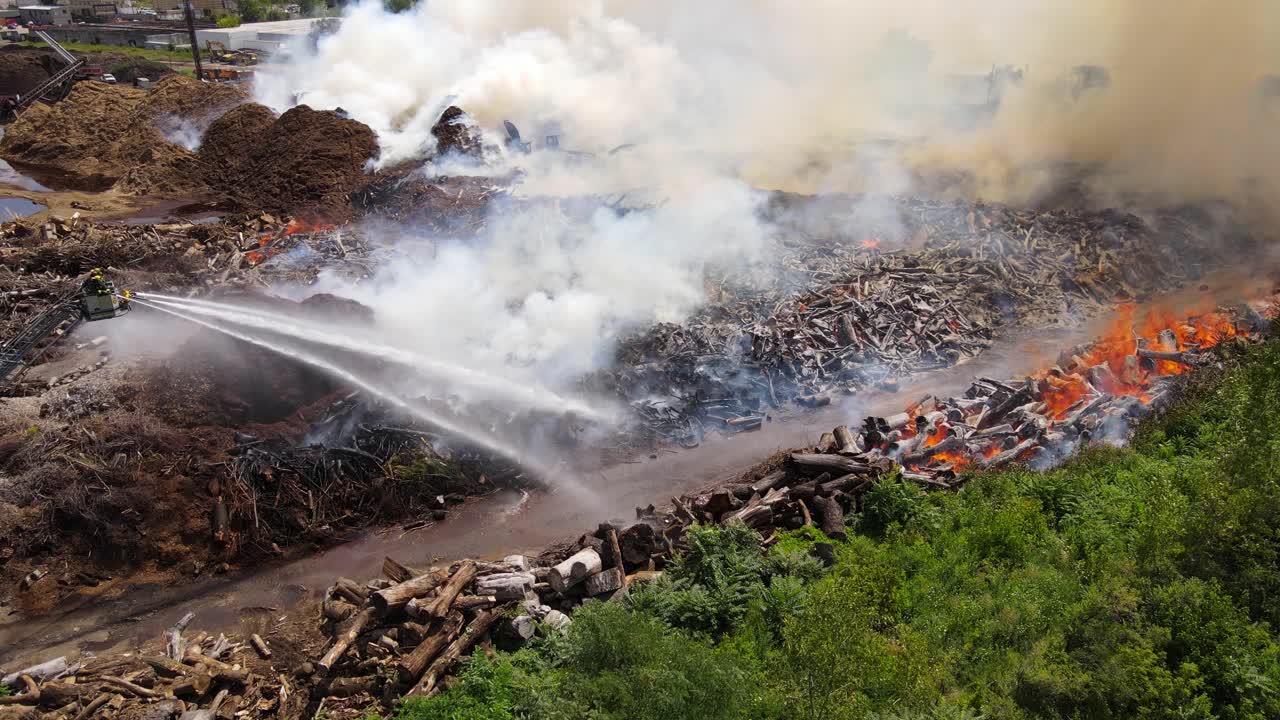 Firefighters fighting massive flames of Mulch company, aerial view