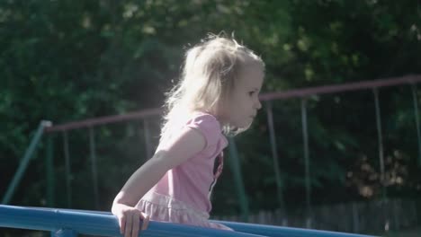 el primer plano de una niña de 4 años en cámara lenta encima de una estructura en un patio de recreo