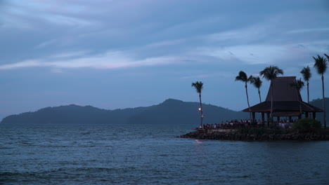 viajeros viendo la puesta de sol vista desde el bar de puesta de sol shangri-la&#39;s tanjung aru resort and spa, kota kinabalu, sabah, borneo con siluetas de palmeras e islotes