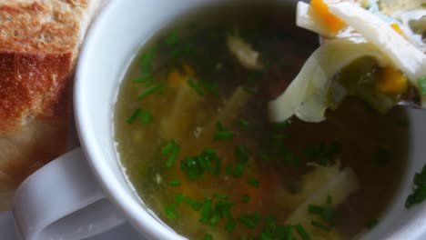 eating hot chicken broth soup with vegetables and small pasta