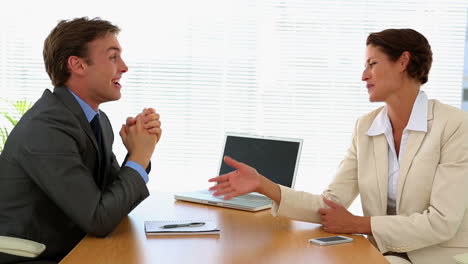 Business-people-talking-together-at-desk