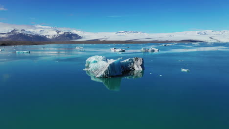 iceberg in calm blue waters of jokusarlon glacial lake - south iceland - drone