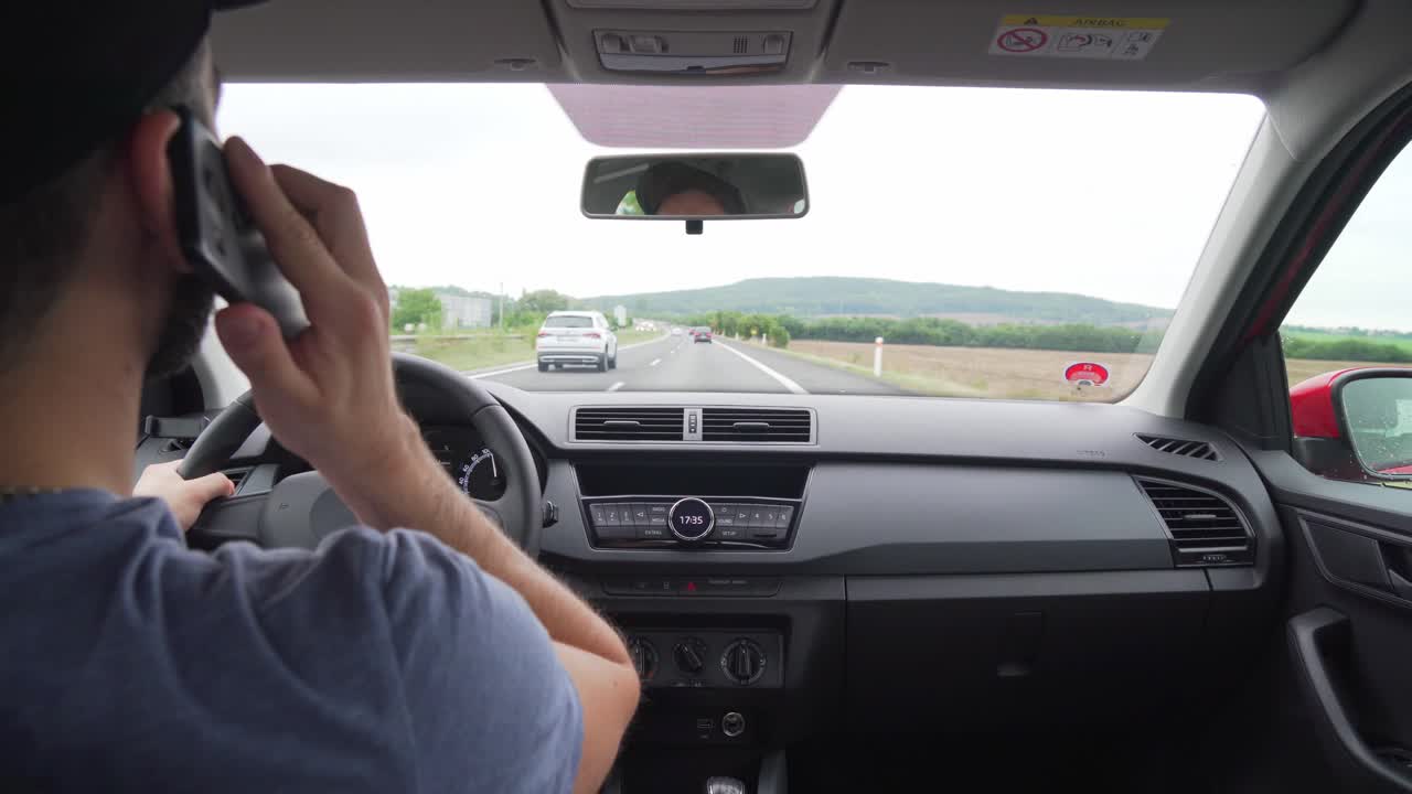 Caucasian man using mobile phone during driving car on highway, closeup interior view from back
