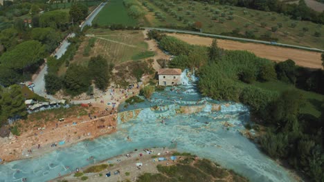 Luftaufnahmen-Der-Ikonischen-Thermalquellen-Von-Saturnia-Cascate-Del-Mulino-Mit-Ihrem-Blauen,-Warmen-Wasser-In-Der-Nähe-Von-Pitigliano-In-Der-Idyllischen-Landschaft-Der-Toskana,-Italien,-Mit-Hügeln-Und-Olivenbäumen