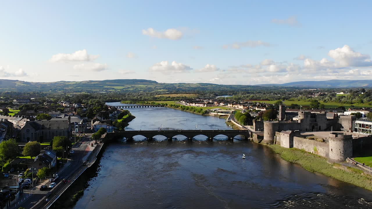 Aerial View of Limerick City, Ireland, Revealing View of Shannon River Riverside With King John's Castle and Residential Neighborhood, Pull Back Drone Shot