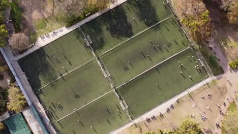 aerial top-down rising directly above soccer players on row of football training fields