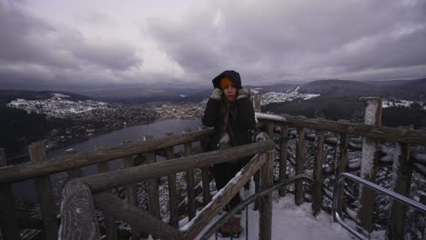 young woman looking out over gerardmer lake in the vosges mountains on a cold snow covered morning