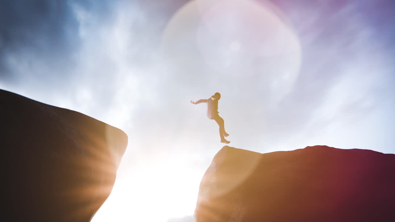 Man Jumps Across a Chasm Between Cliffs at Sunrise
