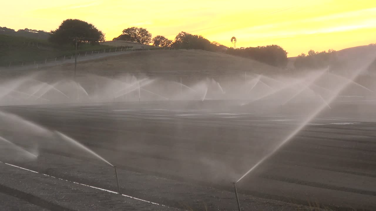 Gli irrigatori innaffiano un campo secco in California durante un periodo di siccità.