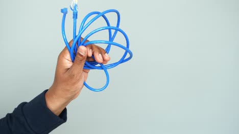 una mano sosteniendo un cable ethernet azul
