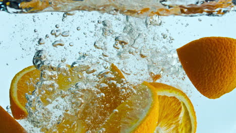 orange wedges splashing water in super slow motion close up. citrus underwater.