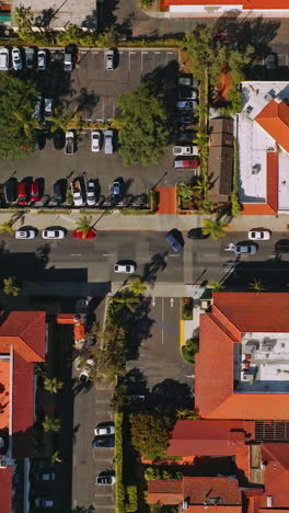 cars moving by the neat cozy streets of santa barbara, california, usa. drone footage over the orange roofs of houses on sunny hot day. vertical video