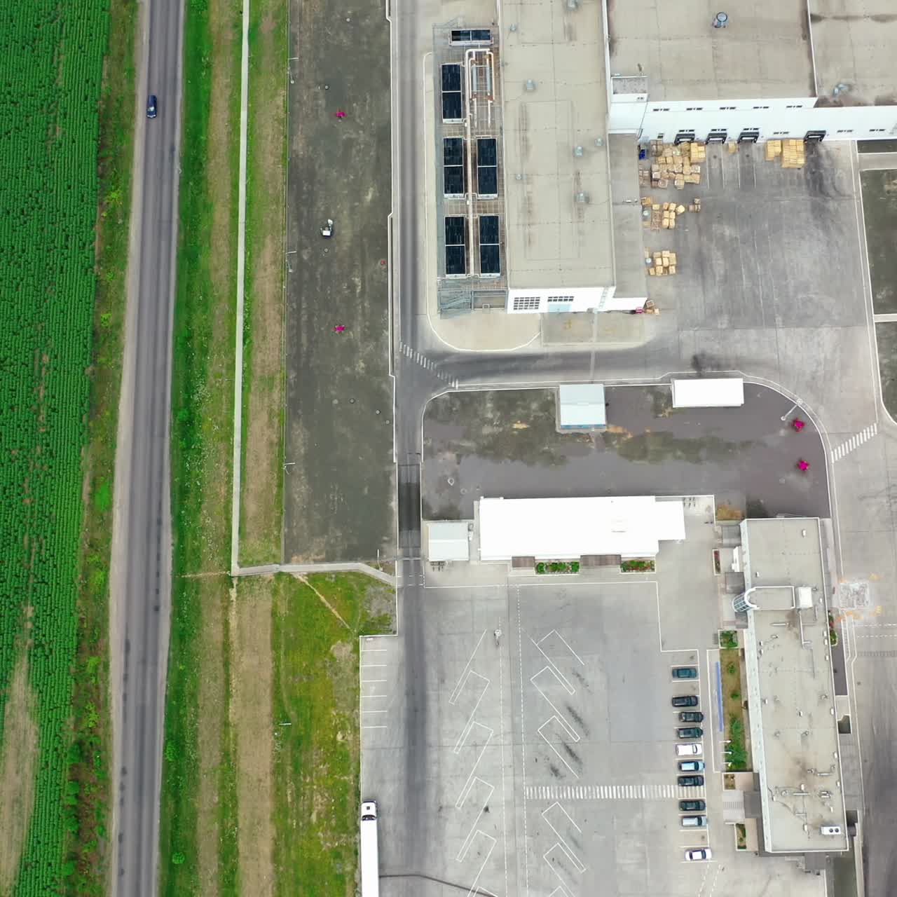 Modern industry and green field. Flight over the large industrial plant near the road and green agricultural plants on field