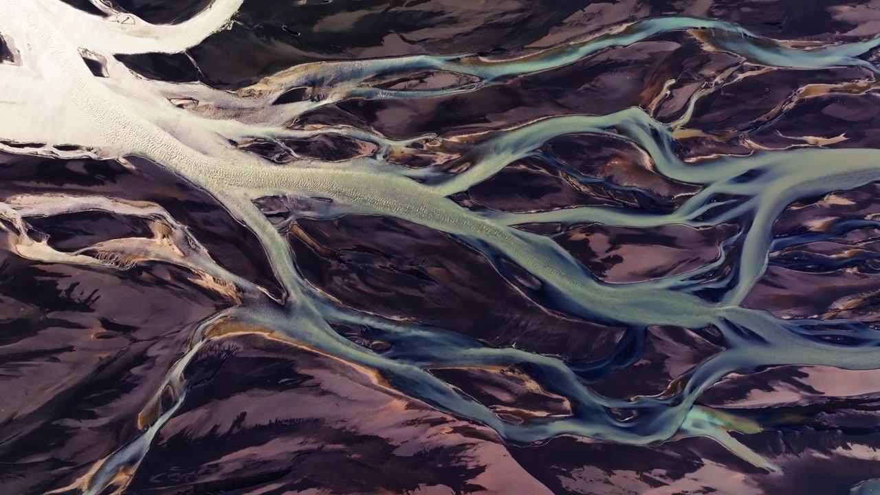 Abstract Veins of Glacial Meltwater Flowing Over Black Volcanic Sand